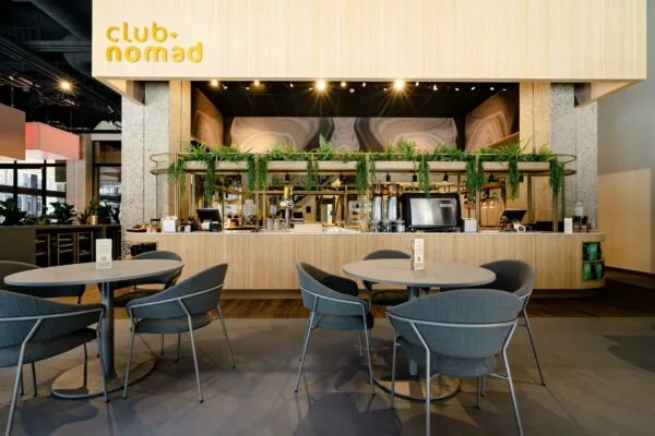 Moderne horecaruimte van Club Nomad aan de Aert van Nesstraat met stijlvolle zitplaatsen en een bar met groene accenten.